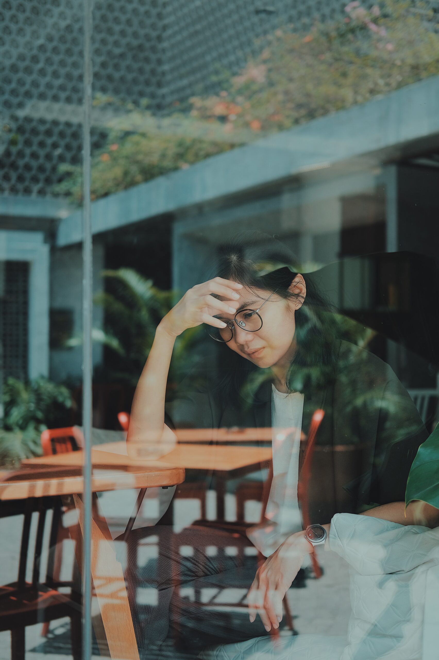 female-sitting-at-table-with-hand-on-head-depressed-winter-blues