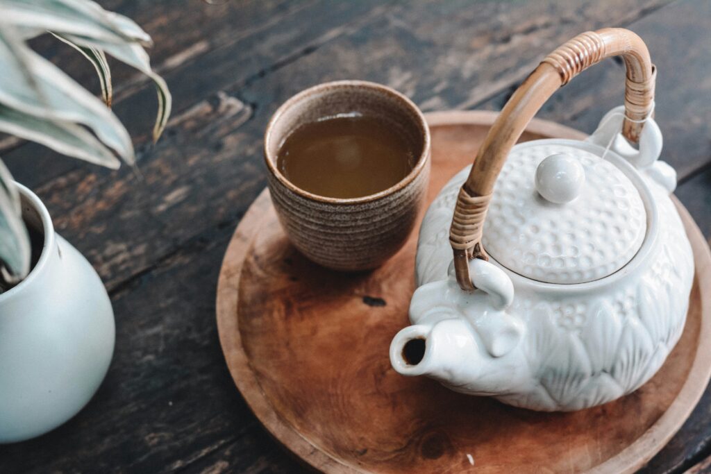 cup of tea and teapot on wooden surface
