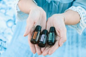 woman-in-blue-dress-with-cupped-hands-holding-three-essential-oil-bottles
