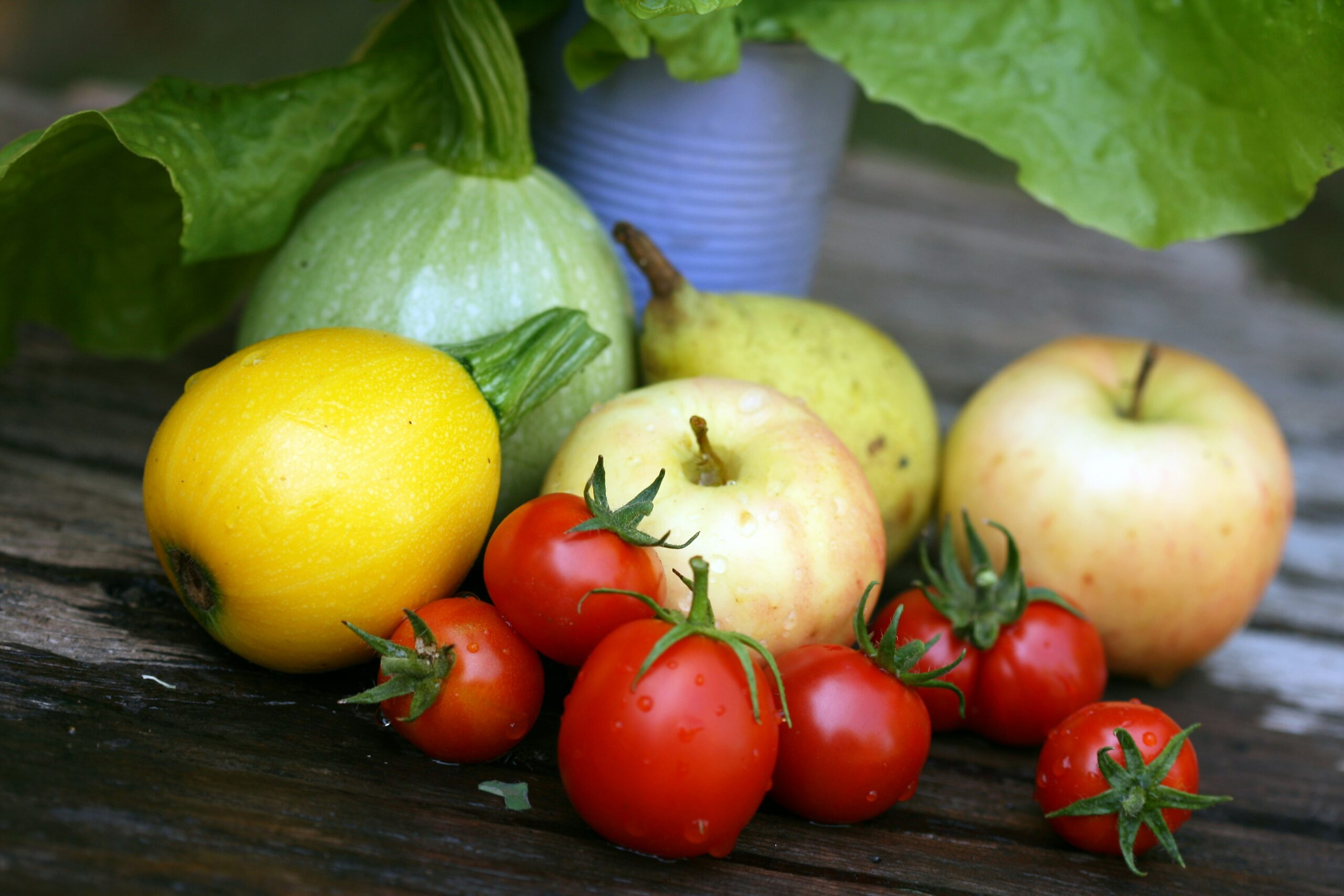 tomatoes-apples-fruits-vegetables-on-wooden-surface-with-leafy-potted-plant