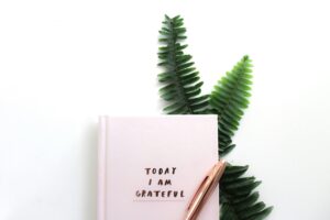 pink-notebook-with-today-i-am-grateful-on-it-and-leaves-on-white-background
