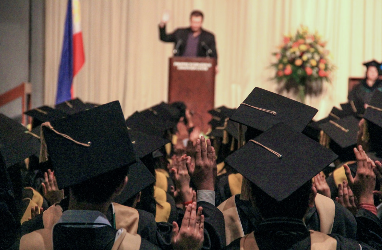 speaker-at-podium-in-front-of-graduating-students-in-caps
