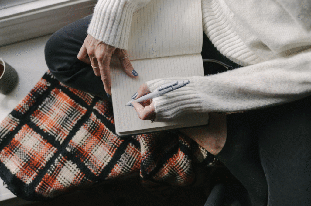 person-in-sweater-writing-in-open-notebook