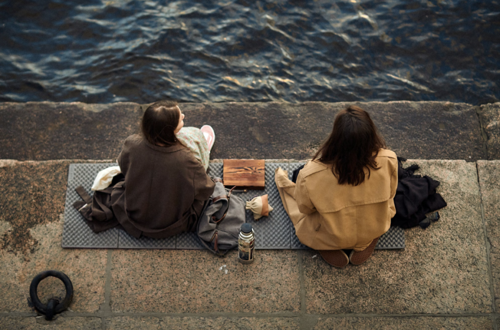 back view of two people sitting by sea