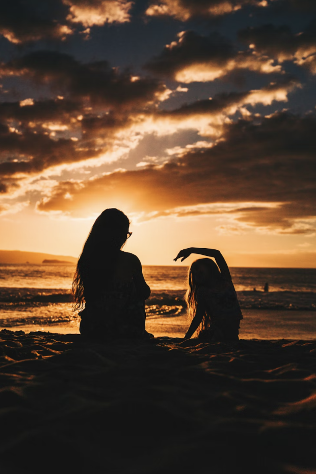 mother and child in shadow in sunset with clouds overhead