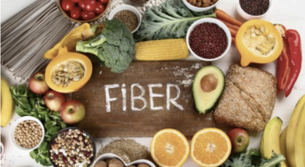 fruits and green vegetables surrounding the word FIBER on wood