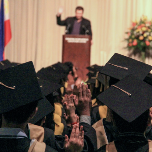 speaker-at-podium-in-front-of-graduating-students-in-caps