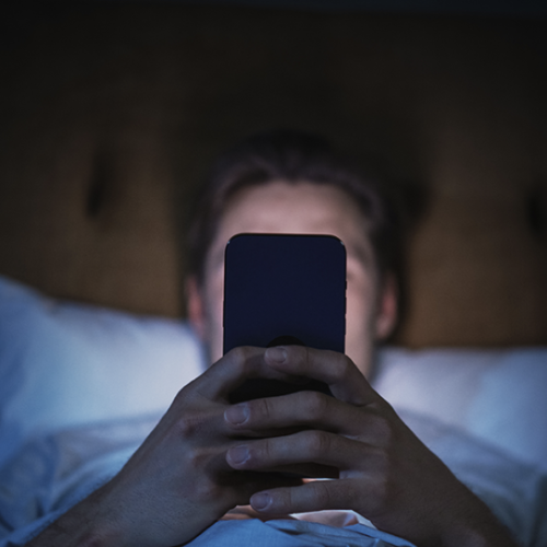 person watching phone in dark room in bed