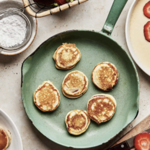 mini pancakes on green pan surrounded by strawberries