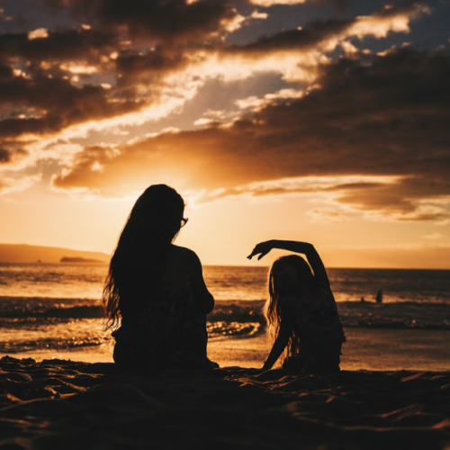 mother and child in shadow in sunset with clouds overhead