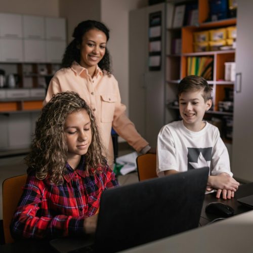 teacher with kids on laptops using AI