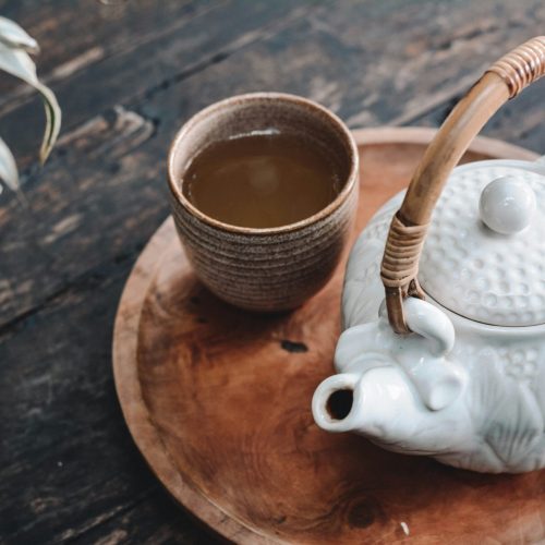 cup of tea and teapot on wooden surface