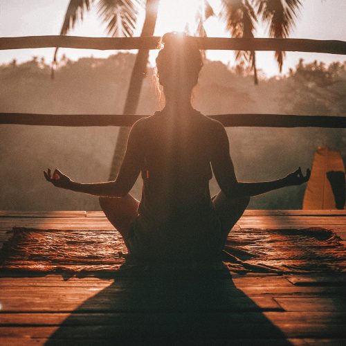dark-figure-of-the-back-of-a-woman-meditating-in-sunny-balcony